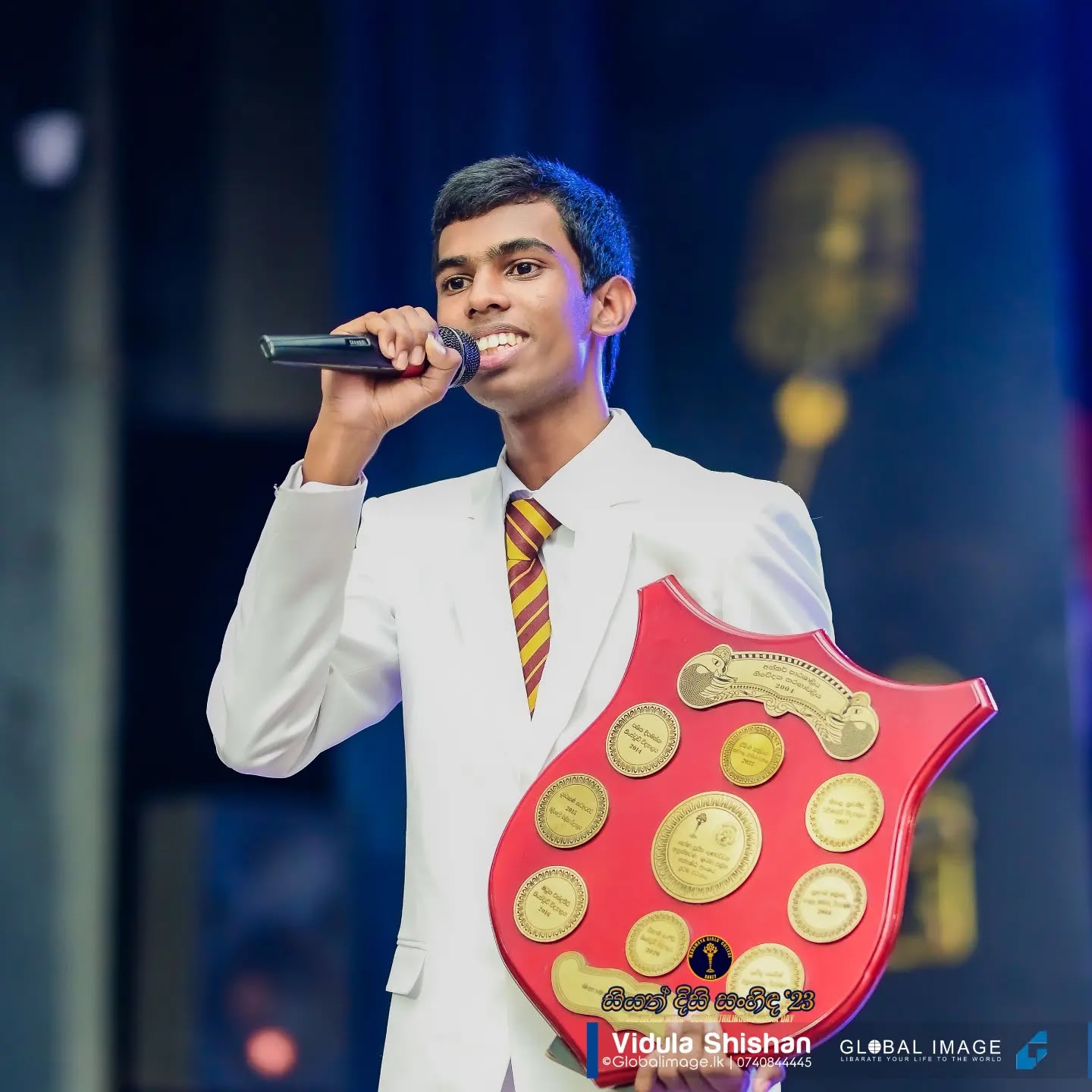 Ramika Risiwara speaking while holding an award shield